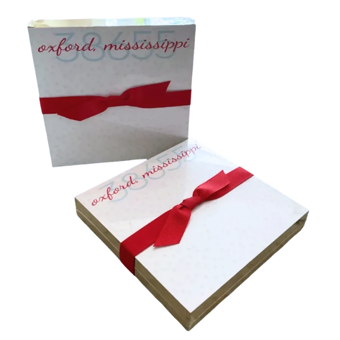 Two square white boxes with the words 'oxford mississippi' in red script and a red ribbon tied around them, shown on a plain white background.
