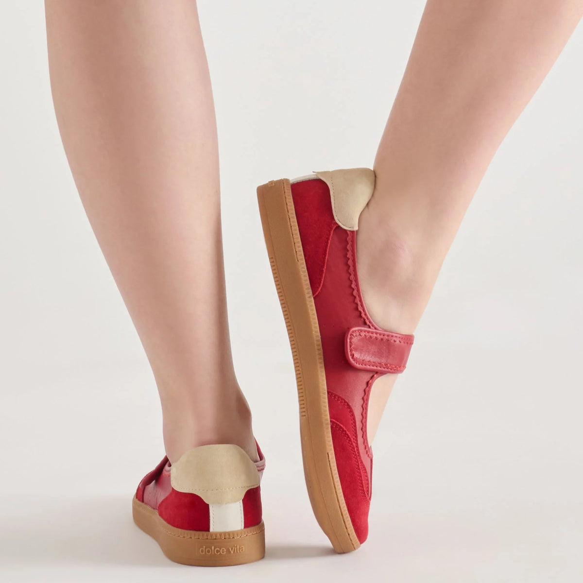 Red shoes with brown soles worn by a person on a light background