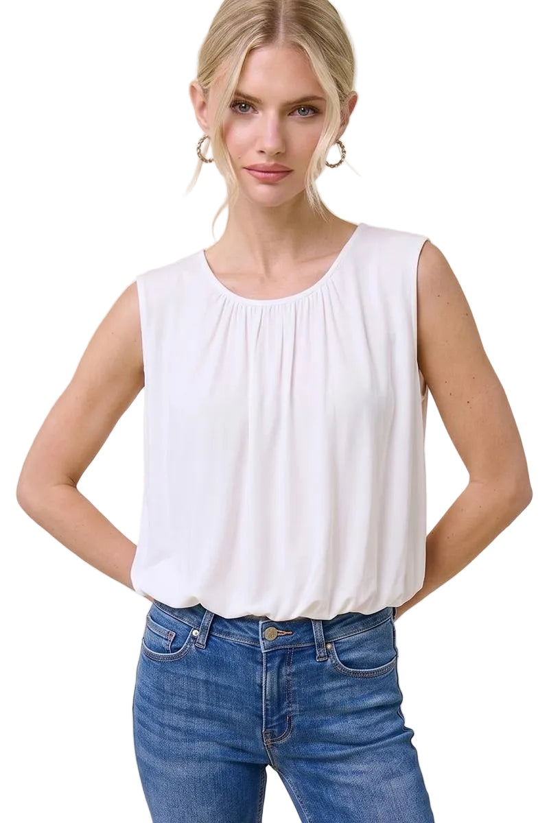 Woman wearing a white sleeveless top and blue jeans on a beige background