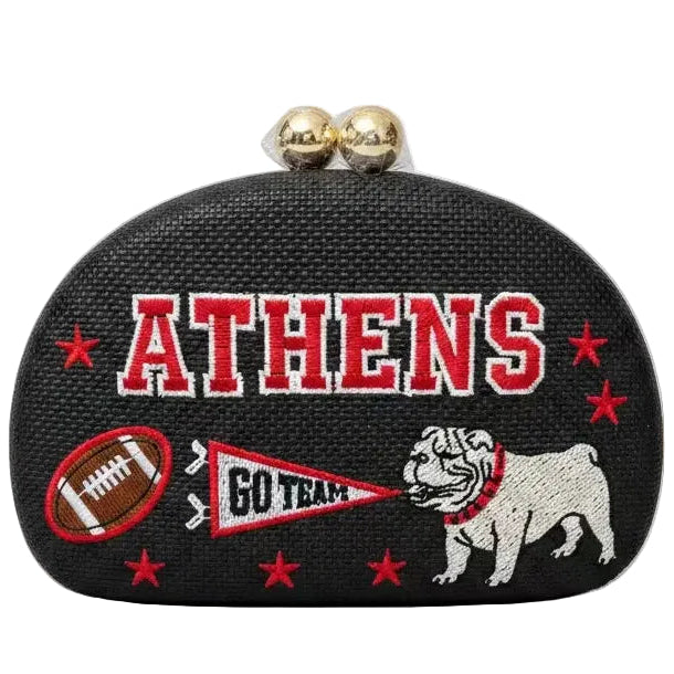A black textured clutch purse featuring embroidered 'ATHENS' in red and white, a bulldog mascot, a football, a pennant reading 'GO TEAM', and red stars, with two gold-tone clasp beads on top, shown against a plain white background.