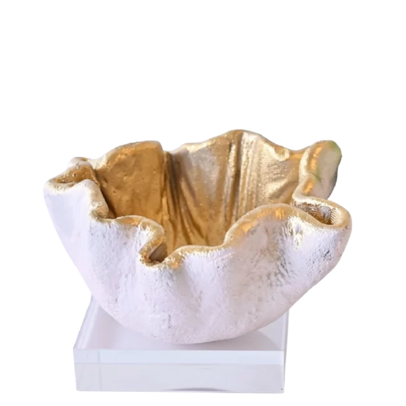 A small sculptural bowl with a textured, organic ruffled exterior in off-white and gold, displayed on a white rectangular pedestal against a solid white background.