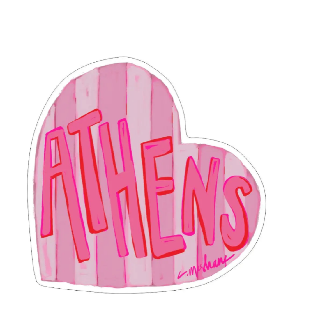 A heart-shaped sticker or decal with pink vertical stripes and the word 'ATHENS' in bold pink letters outlined in red, shown on a plain white background.