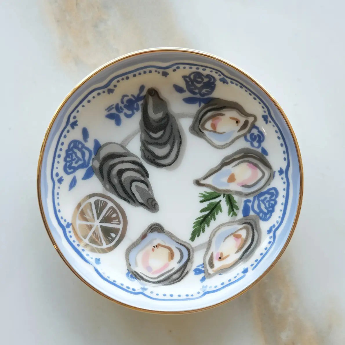 Decorative plate with oyster shells and lemon slices on a marble surface