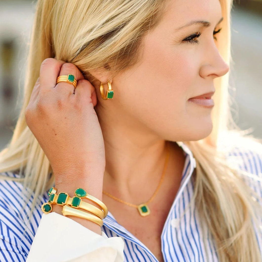 Woman adjusting earrings with a blurred outdoor background
