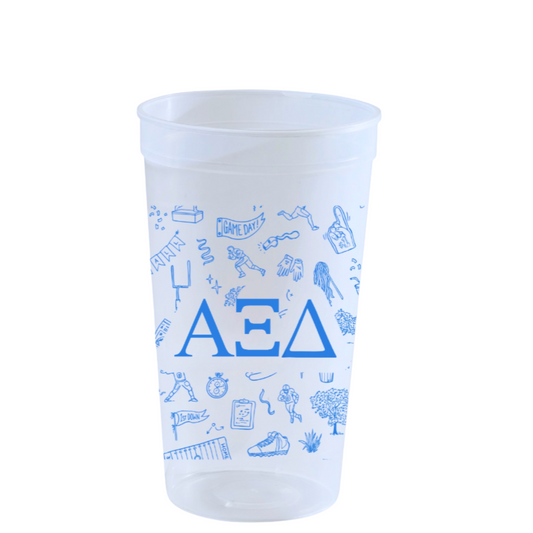 A clear plastic cup with blue Greek letters and small blue doodle illustrations, shown on a plain white background.