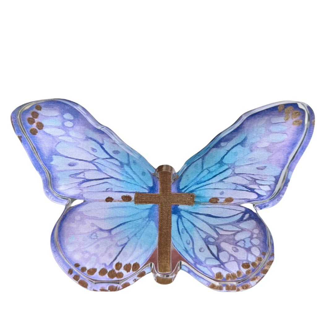 A butterfly-shaped acrylic shelfie with translucent blue and purple wings, gold spotted borders, and a central metallic gold cross, shown on a plain white background.