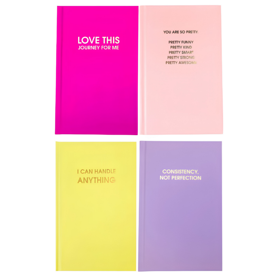 Four hardcover notebooks arranged in a 2x2 grid on a white background. The top-left notebook is bright pink with white text reading 'LOVE THIS JOURNEY FOR ME'.
