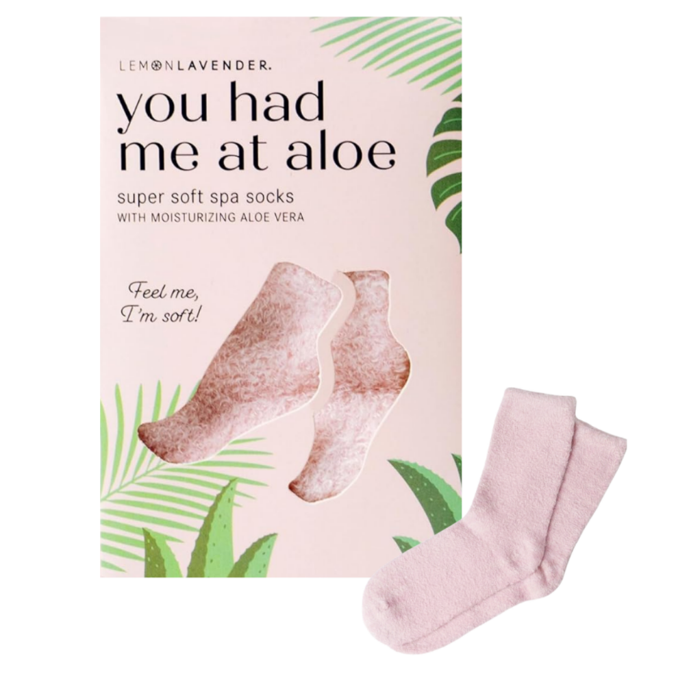 A box of  'You Had Me at Aloe' super soft spa socks next to a pair of light pink socks on a white background.