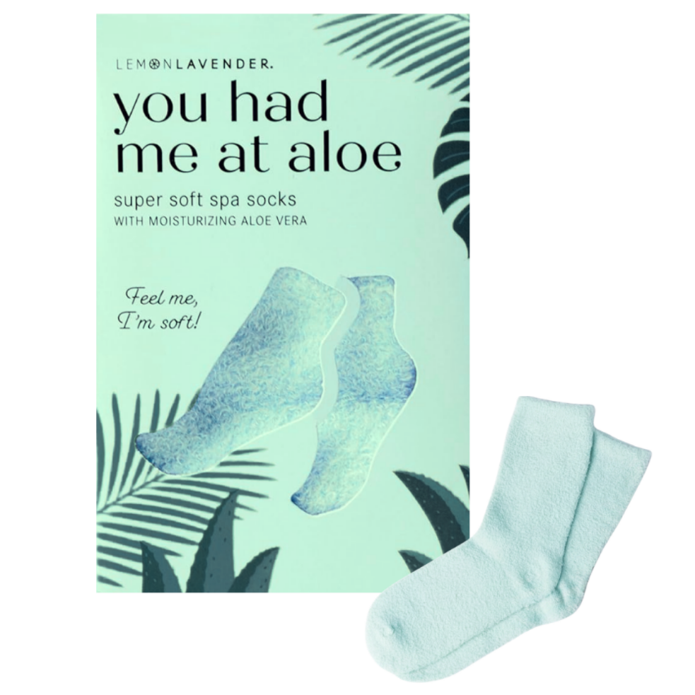 A box of 'You Had Me at Aloe' super soft spa socks next to two light mint green socks on a plain white background.