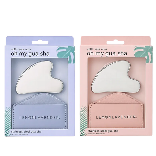 Two boxed gua sha sets on a white background, one in light blue and one in light pink. Each package contains a stainless steel gua sha tool and a small leather pouch branded LEMONLAVENDER.
