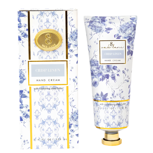 A tube of 8 Crystal Lane Crisp Linen hand cream with a matching floral-patterned box, featuring a blue and white damask design with gold accents.