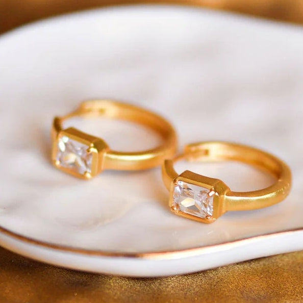 Gold earrings with CZ stones on a white stone in a decorative box.