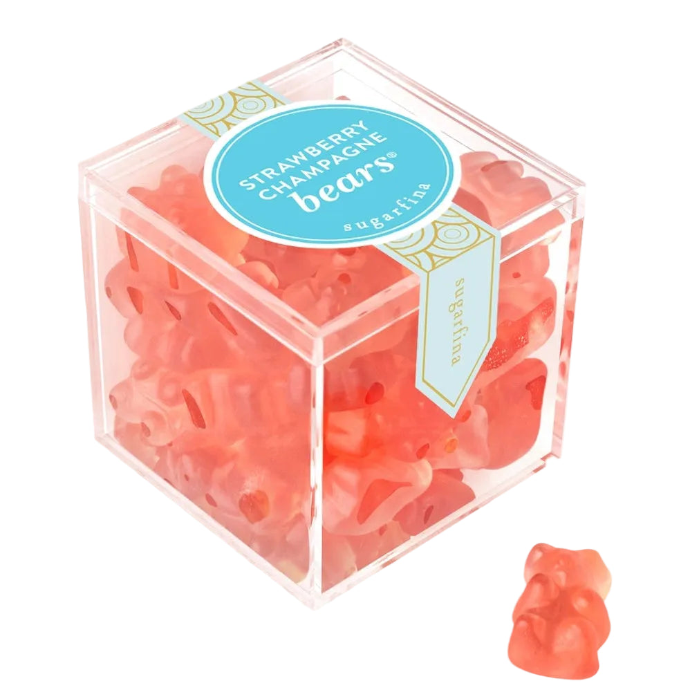 A clear square plastic box filled with strawberry candy bears, with a blue circular label on top, shown on a white background with one candy bear placed outside the box.