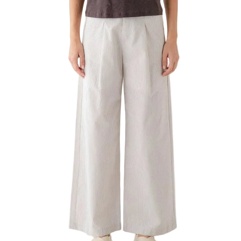A woman modeling a dark brown short-sleeve crewneck t-shirt and light beige wide-leg trousers, paired with beige sandals, against a plain white background.