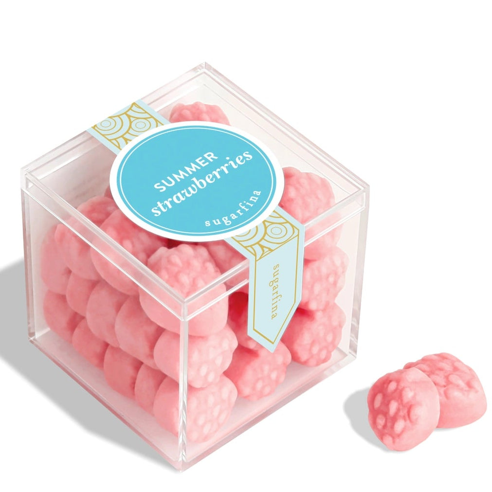 Pink strawberry-shaped candies in a clear cube with a label on a white background