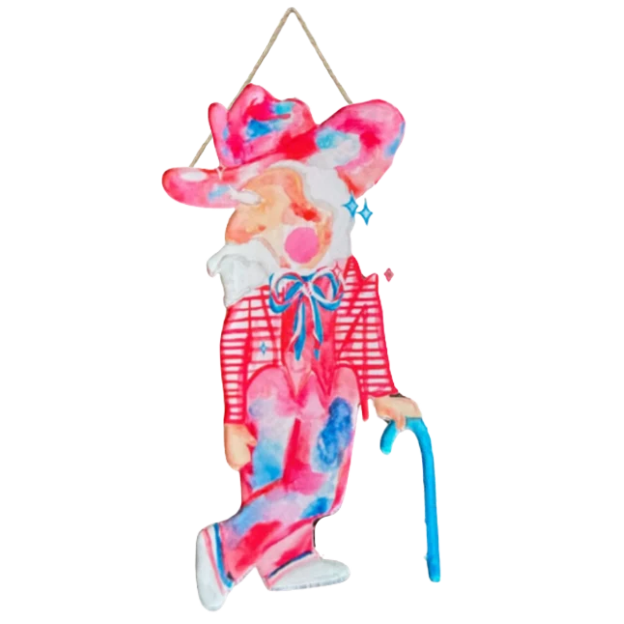 A decorative hanging figurine of a stylized person with a pink and blue tie-dye pattern, wearing a red striped shirt, blue bow tie, and pink hat, holding a blue cane against a plain white background.