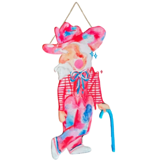 A decorative hanging figurine of a stylized person with a pink and blue tie-dye pattern, wearing a red striped shirt, blue bow tie, and pink hat, holding a blue cane against a plain white background.