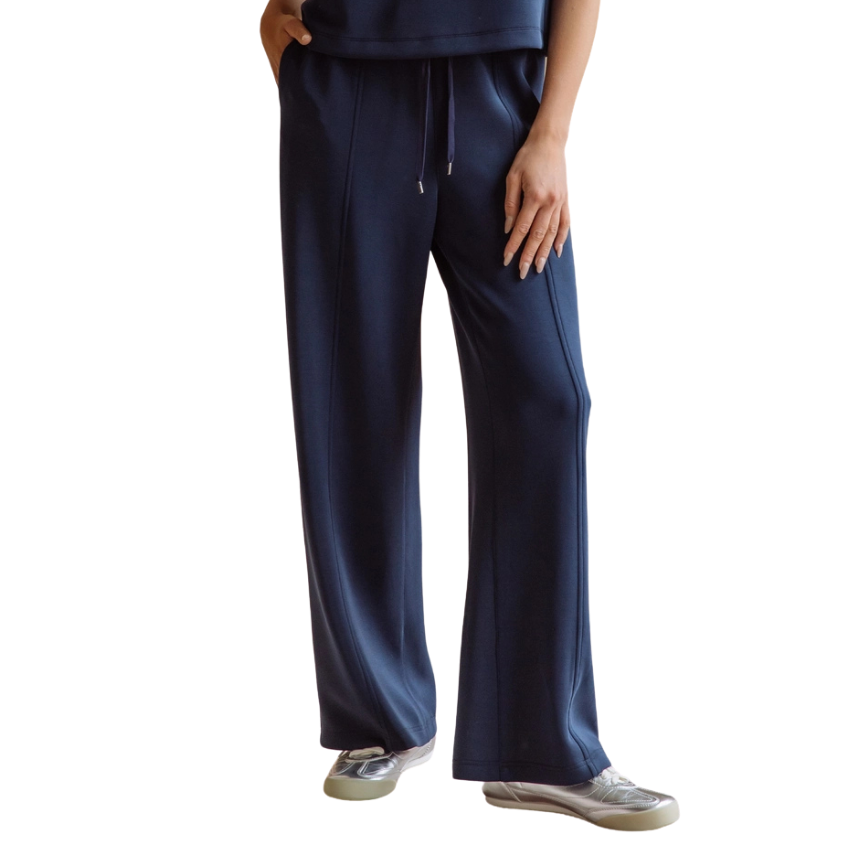 A person wearing navy blue wide-leg sweatpants with a drawstring waist, paired with a matching navy top and gray sneakers, shown against a plain white background.