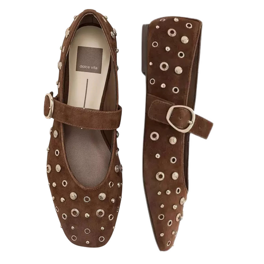 A pair of brown suede Mary Jane flats with silver-tone metal studs and circular cutout details, shown from top and side views on a white background. The insole displays the brand name 'Dolche Vita'.