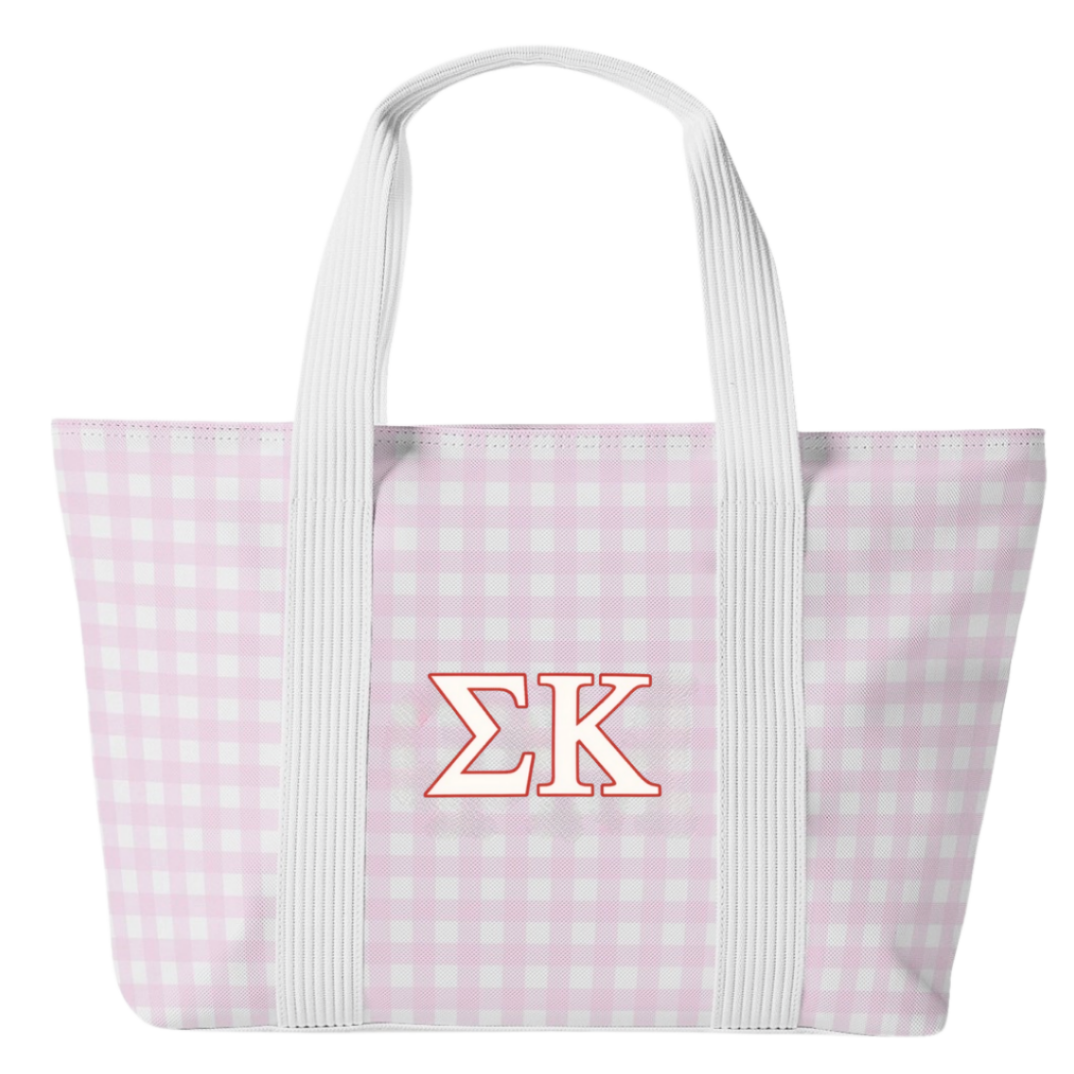 A light pink and white gingham tote bag with white shoulder straps and a red-outlined Greek letter logo 'ΣK' on the front, set against a plain white background.