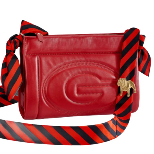 A red leather shoulder bag with a wide red and black striped ribbon strap, featuring a large embossed 'G' on the front and a gold BULLDOG logo charm.