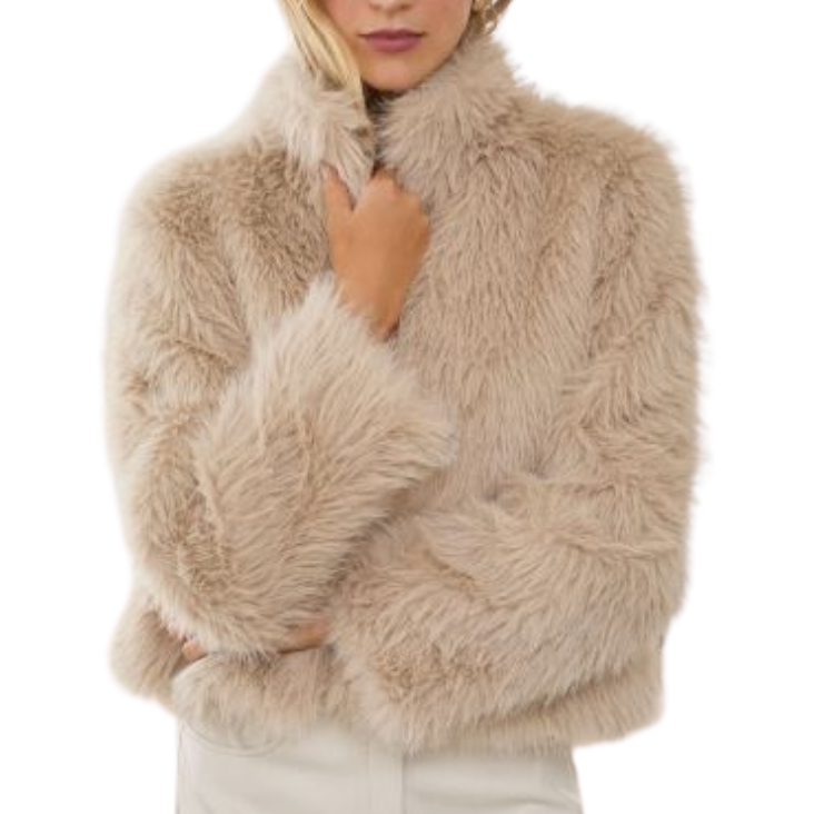 A woman modeling a fluffy faux fur cropped jacket in a light beige color, paired with a white mini skirt, against a solid white background.