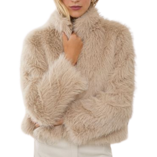 A woman modeling a fluffy faux fur cropped jacket in a light beige color, paired with a white mini skirt, against a solid white background.