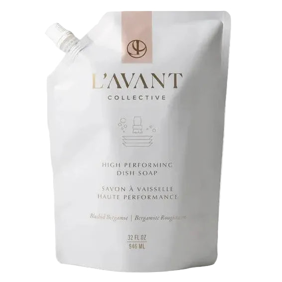 A white stand-up pouch of L'Avant Collective dish soap with a small pink accent band and gold lettering, photographed on a clean white background with a soft shadow.
