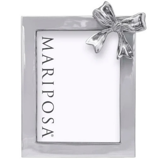 A square silver metallic frame with a white insert card featuring the vertical text 'MARIPOSA' in black, accented by a small silver bow at the top right, shown on a plain white background.