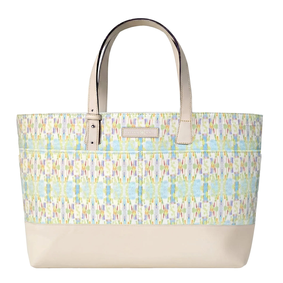 A tote bag with a cream-colored base and handles, featuring a colorful ikat patterned upper body in shades of blue, green, yellow, and pink on a white background.