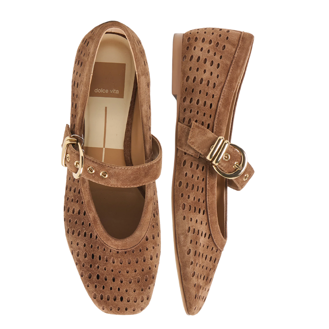 A pair of brown suede Mary Jane shoes with perforated detailing, gold-tone buckle straps, and a small gold charm, shown from a top-down view on a white background.