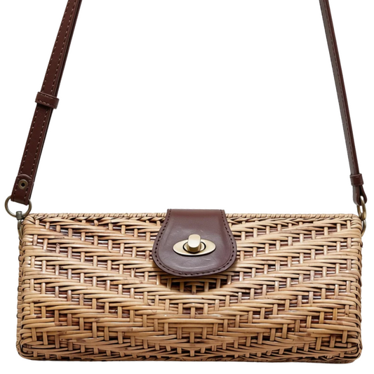 A woven straw shoulder bag with dark brown leather trim and strap, featuring a gold-tone turn-lock closure on the front flap.