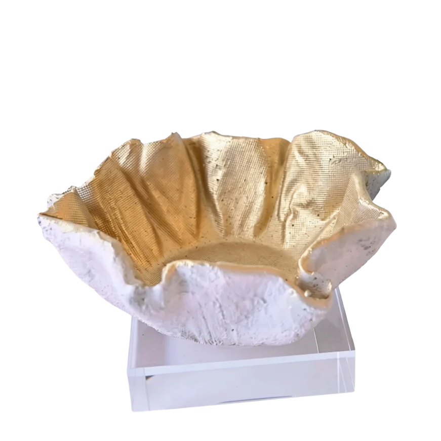 A decorative bowl with a textured, organic shape, featuring a metallic gold interior and a white exterior, displayed on a small white pedestal against a solid white background.