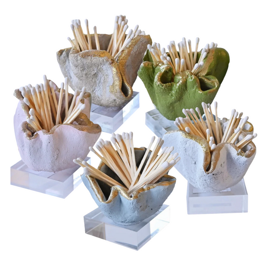 Five small sculptural toothpick holders in assorted earthy colors, each holding multiple toothpicks and mounted on a clear acrylic base, shown on a white background.