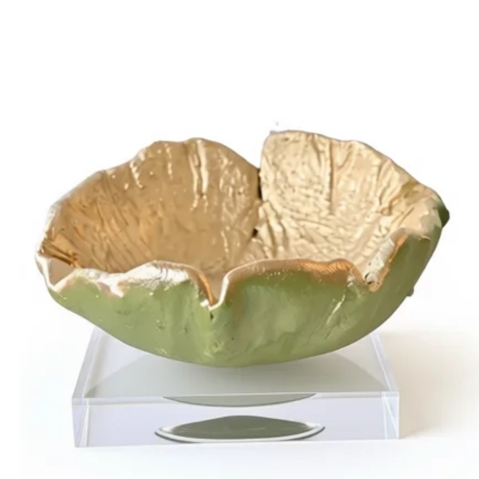 A handmade ceramic bowl with a textured, organic shape, featuring a light green exterior and a metallic gold interior, displayed on a clear acrylic stand against a white background.