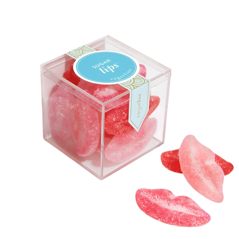 Pink candy shaped like lips in a clear box with a blue label on a white background
