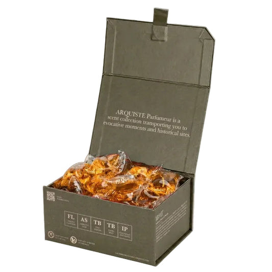 An open dark olive green perfume gift box containing multiple individually wrapped amber-colored perfume bottles, shown on a plain white background.