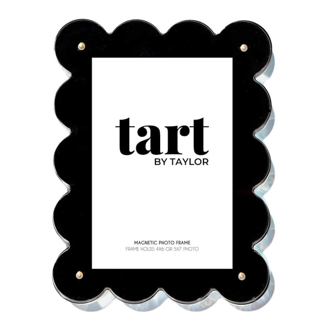 A black scalloped-edge acrylic photo frame with a white insert card displaying the brand name 'tart BY TAYLOR'.