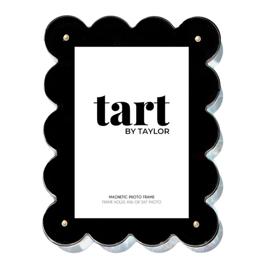 A black scalloped-edge acrylic photo frame with a white insert card displaying the brand name 'tart BY TAYLOR'.