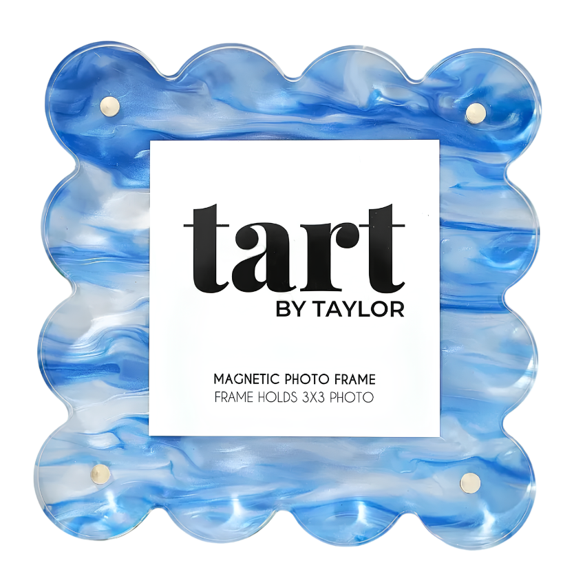 A scalloped magnetic photo frame by Tart by Taylor, made of blue and white marbled resin, with a white paper label in the center.