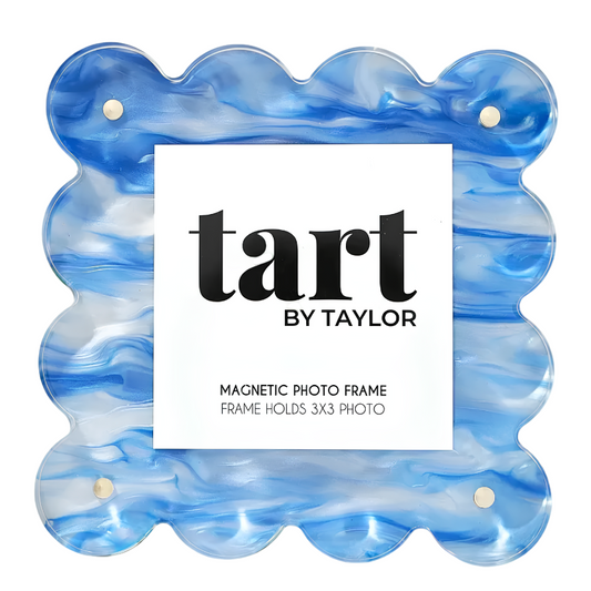 A scalloped magnetic photo frame by Tart by Taylor, made of blue and white marbled resin, with a white paper label in the center.