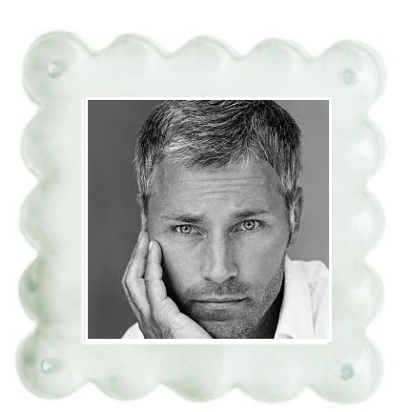 A square white scalloped-edge photo frame or plaque with a black-and-white portrait of a man printed in the center, shown on a plain white background.