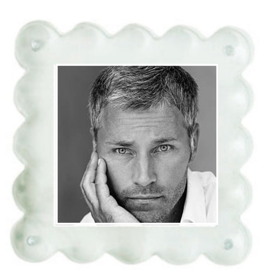 A square white scalloped-edge photo frame or plaque with a black-and-white portrait of a man printed in the center, shown on a plain white background.