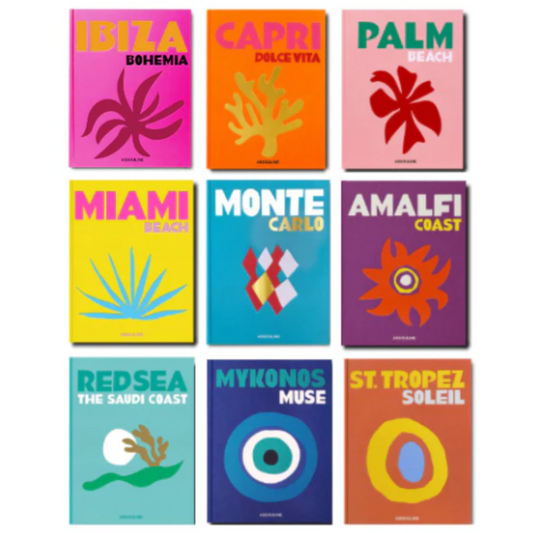 Assouline travel books featuring Izu, Capri, Palm, Miami, Monte Carlo, Amalfi, Red Sea, Mykonos, and St Tropez. Each has a different bright background color with a stylized sun or abstract coastal graphic and the destination name at the top