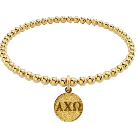 A gold beaded stretch bracelet with a round textured pendant engraved with the Greek letters Alpha Chi Omega (ΑΧΩ), shown on a plain white background.