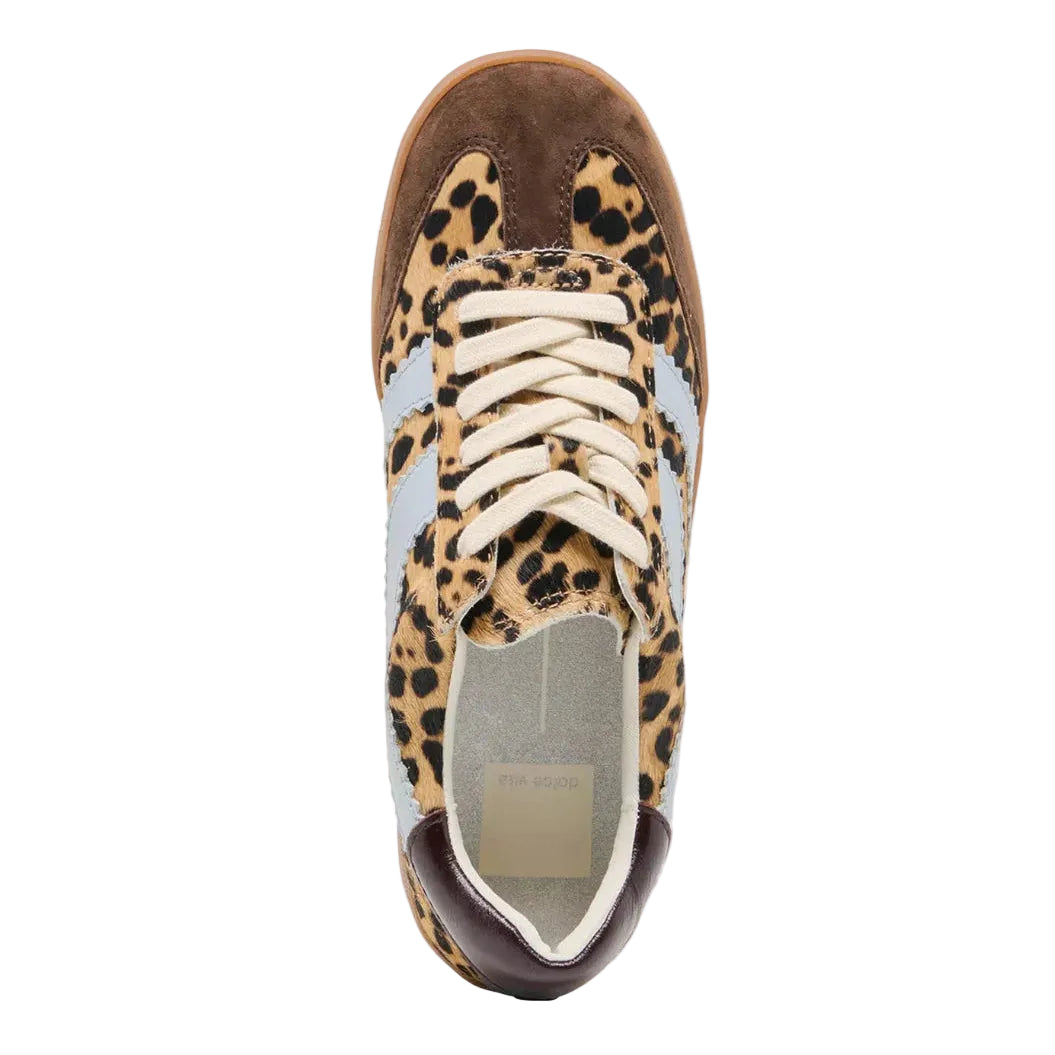 A single low-top sneaker shown from a top-down view on a light gray background. The shoe features a leopard print pattern in beige, brown, and black on the upper, cream laces, a brown suede toe cap, and light blue side stripes.