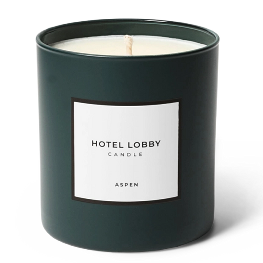 A dark green glass jar candle with a white label reading 'HOTEL LOBBY CANDLE' and 'ASPEN' on a clean white background.