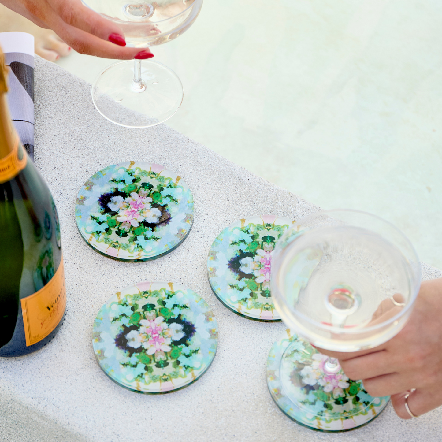 Floral coasters on a table with a bottle of champagne and glasses.